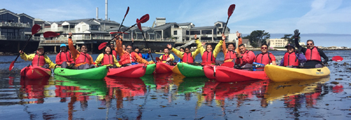 row of kayakers in front of the Monterey Bay Aquarium
