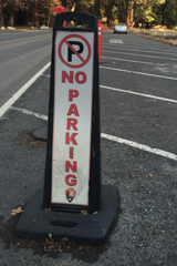 no parking sign and car parked just beyond it