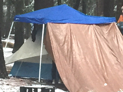 dining canopy over a tent, with a tarp sticking out the side