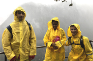 three people at a railing in bright yellow rain jackets and pants