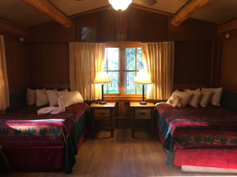 2 double beds, nightstands with lamps, window in a cabin bedroom