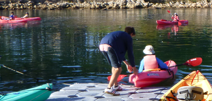 kayak on large floating platform being slid into the water