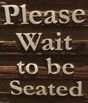 sign that says please wait to be seated