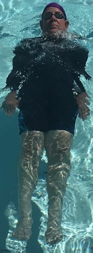 man floating on his back with his legs slightly sinking down into the water
