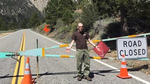 man standing in front of road closed barrier