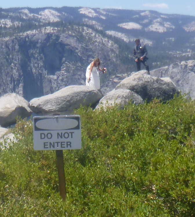 Yosemite bride and groom at Glacier Point out at edge