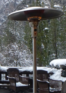 lit tall propane heater and snow covered furniture.