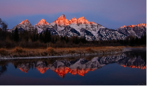 pink topped mountains reflected in very blue lake