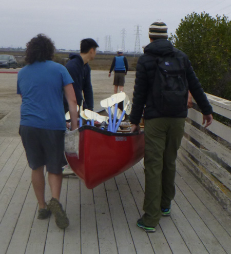 men carrying boat full of paddles