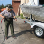 park ranger sprays a boat with a hose under pressure