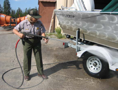 park ranger sprays a boat with a hose under pressure
