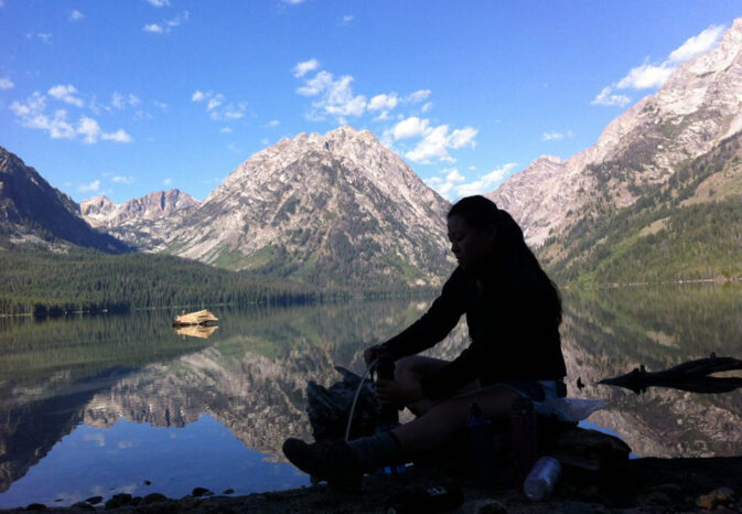 woman silhouetted in foreground of a lake