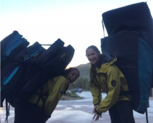 2 women with stacks of crash pads on their backs
