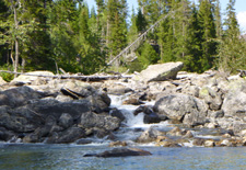 small stream flowing over rocks into lake