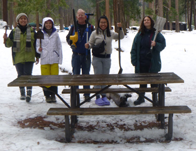 line of people with tools standing behind a picnic table