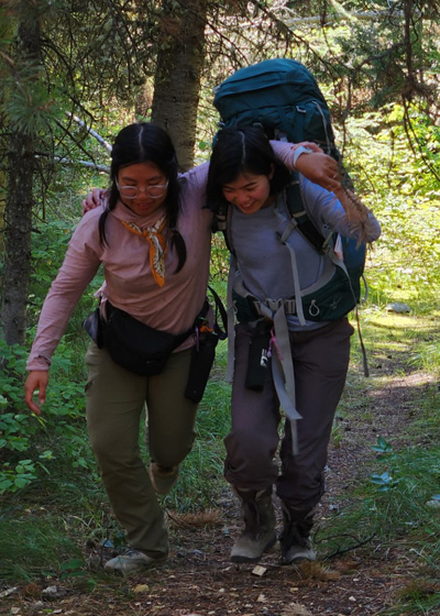 two women on trail, one assisting the other