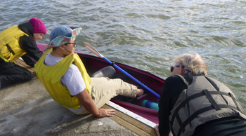 woman sitting on a dock with her feet in a kayak in the water
