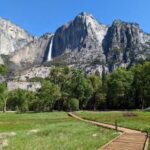 boardwalk across meadow in foreground waterfall behind