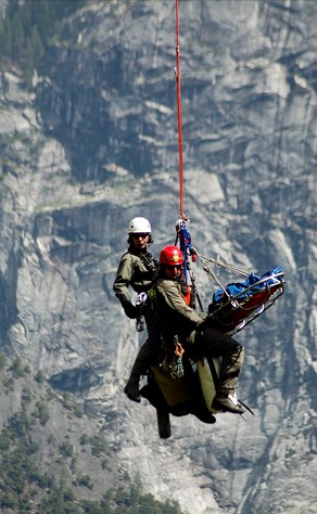 Two rangers strapped to a litter hanging in the air