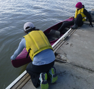 2 people lift kayak off dock into water