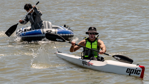 man in kayak tows a man in an inflated raft