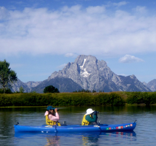 two people in a kayak with binoculars watching ducks