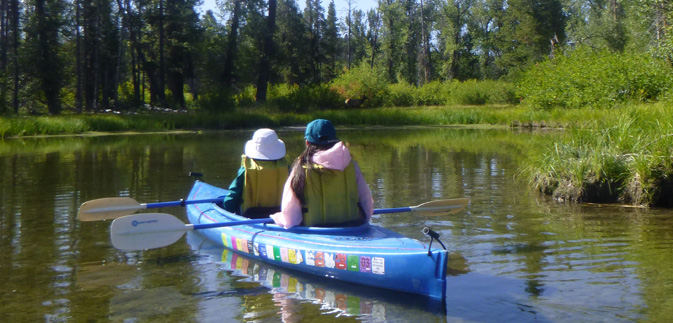 two women in kayak watch elk family