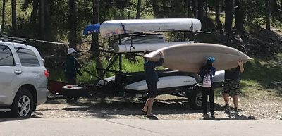 people lifting kayak towards ground from trailer