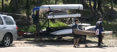 three people carry kayak to shore