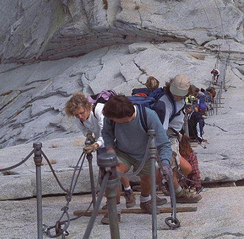 people crowded together holding cables on half dome