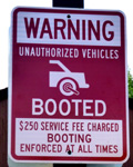 sign says unauthorized vehicles booted