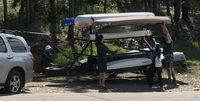 people reaching up for a kayak on a trailer