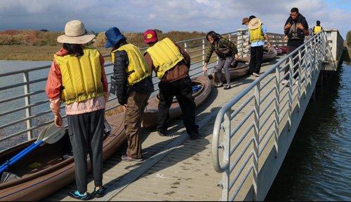 people standing next to a row of kayaks