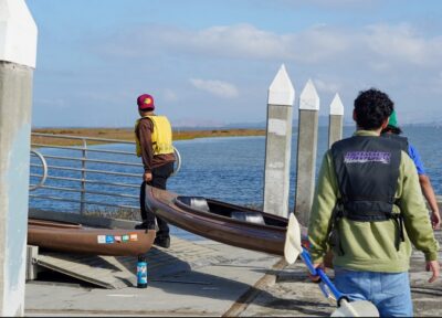 people carrying kayaks along a dock