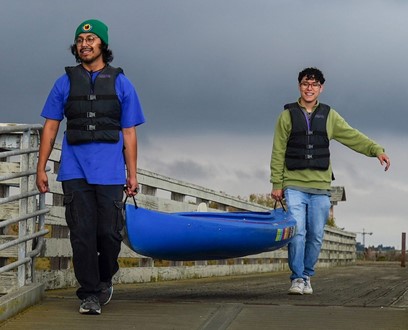 two people carrying a kayak down a ramp