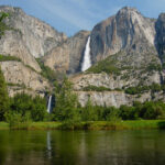 river in foreground, cliff behind with waterfall
