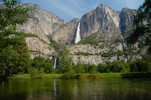 river in foreground, cliff behind with waterfall