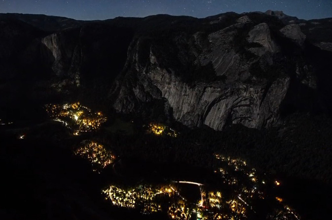 lights of buildings and roads with cliffs behind