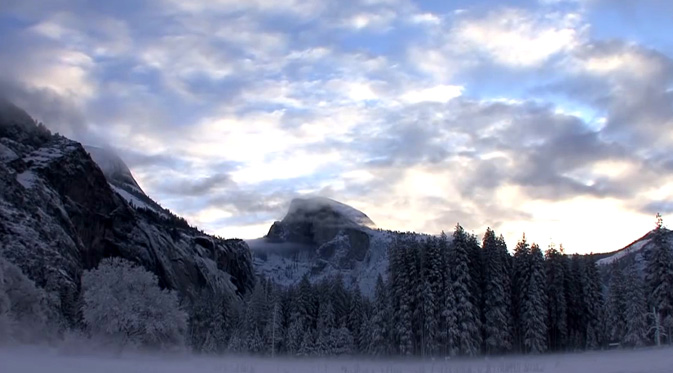 cloudy sky above Half Dome, fog on snowy meadow below