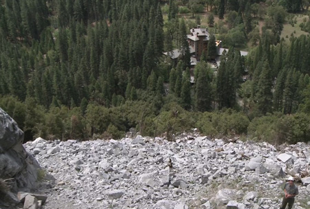 man stands on rocky slope above hotel