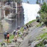 people on stone stairs with waterfall behind them
