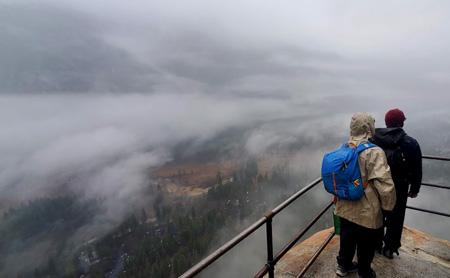 people at railing with low clouds all around their view