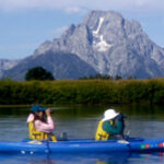 two people in a kayak wearing hats with large brims