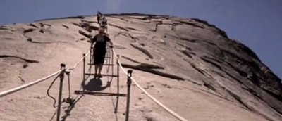 people with hands on cables going up half dome