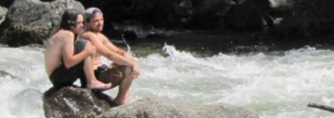 two men on a rock above whitewater