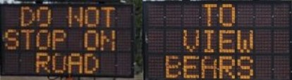 side by side electronic signs say do not stop on road to view bears