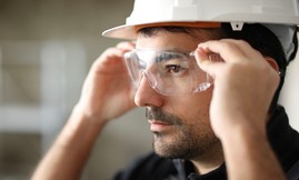 man adjusts safety goggles on his face