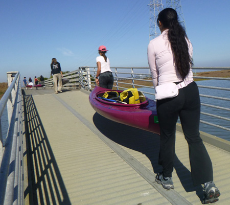 people carrying a kayak up a ramp