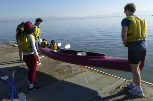 2 people lifting a kayak into the water