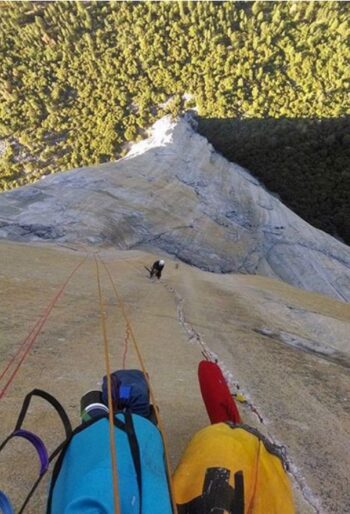 looking down a rock face at a climber
